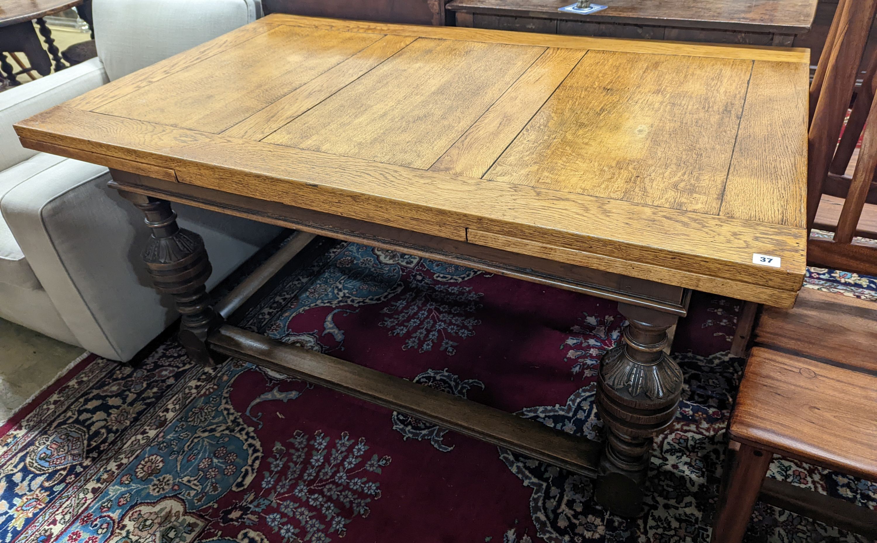 An 18th century style pale oak draw leaf dining table on carved baluster legs, length 242cm extended, depth 91cm, height 75cm